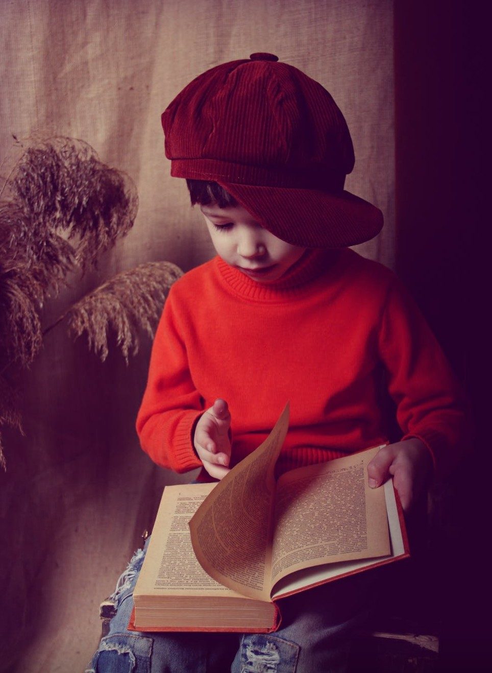 Young boy in a red cap turning the pages of a book